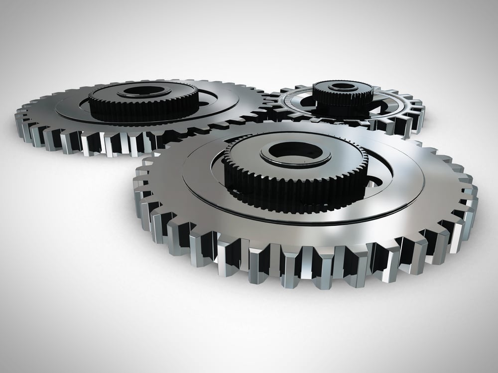 Metallic 3D cogwheels engaged - over a gray background